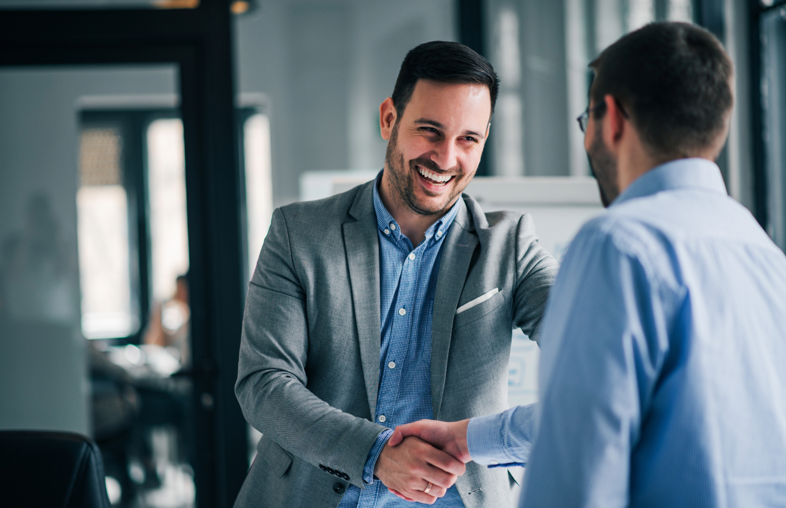 Persona mentre sorride mentre stringe la mano ad un'altra persona